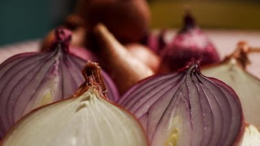 Tahta kesme tahtasına yerleştirilmiş kırmızı, sarı ve beyaz soğanlar da dahil olmak üzere çeşitli soğan parçalarının yakın çekim görüntüleri. Mutfak, yemek ve sağlıklı besinler için mükemmel.