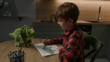 Genç bir çocuk evinde oturuyor, oyuncak dinozorunu dikkatlice çiziyor, yaratıcılık ve hayal gücünü yakalıyor, rahat, evcil bir ortamda.