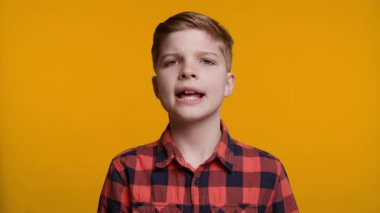 Genç bir çocuk başını bir aşağı bir yukarı sallayarak onay ya da mutabakat işareti veriyor. Parlak sarı arka plan, jestinin olumlu ve olumlu havasını arttırır..