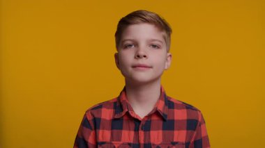 Genç bir çocuk başını arkaya eğiyor, geniş gözlerle bakıyor ve inançsızlık ifadesi sergiliyor. Parlak sarı arka plan onun şaşırmış ve şaşırmış tepkisini arttırır..