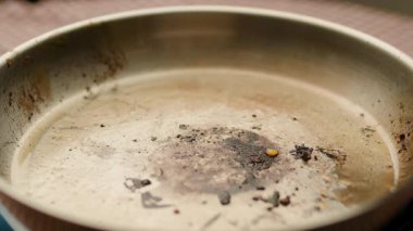 Yüzeye yapışmış yanmış yemek artıkları ve ızgara parçalarıyla kirli bir kızartma tavasının yakın çekimi. Mutfak, yemek ve temizlik için mükemmel..