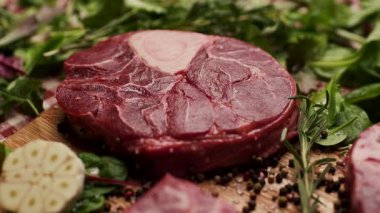 Biberiye dalının çiğ Osso Buco bifteğine zeytin yağı sürerken yakın plan bir fotoğrafı. Aşçılık, aşçılık ve gurme yemek temaları için mükemmel.