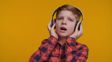 Kulaklık takan genç bir çocuk kameraya bakarken, müzik tutkusu ve heyecanını ifade ederken neşe içinde şarkı söylüyor. Parlak sarı arka plan onun enerjik ve mutlu performansını arttırır..