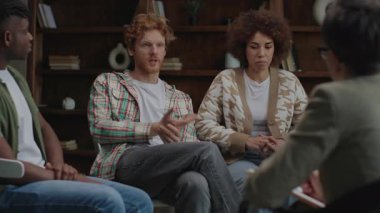Çift grup terapisinde açık açık evlilik sorunlarını tartışıyor, destekleyici bir ortamda diğer katılımcılardan empati ve rehberlik istiyor..