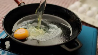 Çiğ yumurtanın çatırdadığı ve sıcak bir tavanın üzerine düştüğü yakın plan bir çekim, temas üzerine cızırtı. Yemek pişirmek, kahvaltı hazırlamak ve yemek hazırlamak için mükemmel..