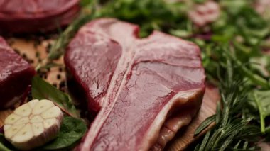 Köy ahşap bir masada sergilenen T-bone ve Osso Buco kesikleri de dahil olmak üzere farklı türde çiğ biftek. Aşçılık, yemek pişirme ya da kasaplık için mükemmel.