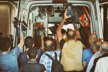 Kameramanlar ve fotoğrafçılar bir ambulansın içinde neler olup bittiğini kaydetmeye çalışıyorlar.