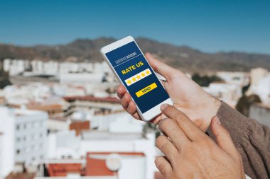 Bir ürünü veya servisi cep telefonuyla değerlendiren adam.