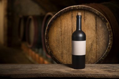 Mükemmel kırmızı şarap şişeleri, şarap bardağı, fıçı ve tirbuşon kırsal bir masa üzerinde: geleneksel şarap yapımı ve şarap tatma konsepti. Yüksek kalite fotoğraf