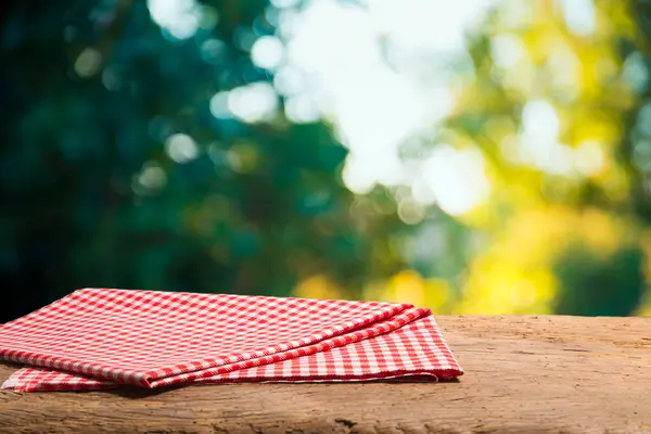 Empty table decorated with red checkered towel food advertisement display. Tabletop with empty space. Picnic table on wooden deck,blurred backdrop. Promotion background. High quality photo