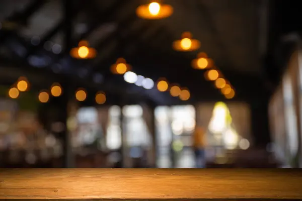 image of wooden table in front of abstract blurred background of resturant lights . High quality photo
