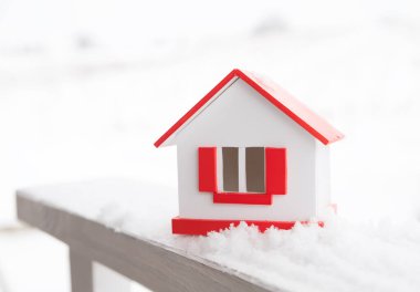 Kışın ev - ısıtma sistemi konsepti ve soğuk karlı hava ve örgü şapkalı bir ev modeli. Yüksek kalite fotoğraf