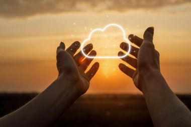 Gün batımı arkaplanına karşı eller veri bulutunu destekler.