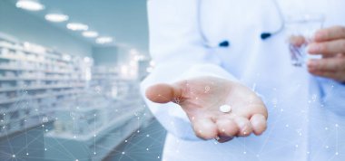 Doktor, bir eczanenin arka planında hastalıkların tedavisi için bir hap gösteriyor..