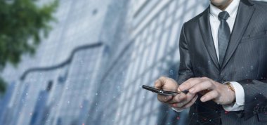 A businessman works on the phone on the Internet against the backdrop of a business center.