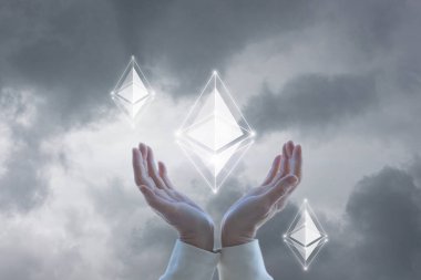 Ethereum destek konsepti. Eller gökyüzü arkaplanındaki Ethereum simgesini destekler.