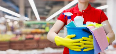 Süpermarketin bulanık arka planında kova ve temizlik ürünleriyle temizleyici.