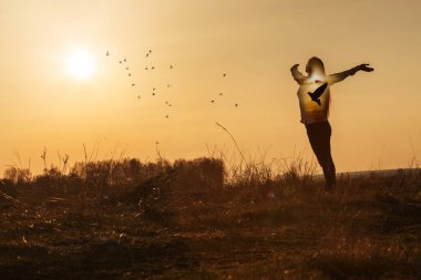 Mutluluk ve umut kavramı. Güneşli bir günbatımının arka planında, içinde güvercin olan bir kadın..