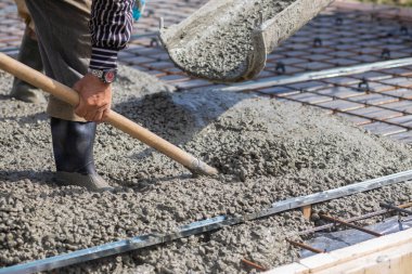 İşçi inşaat demirinde dikilirken kürekle beton topluyor..