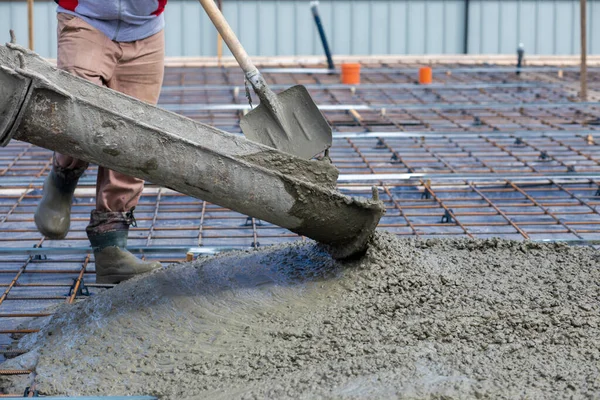 A worker cleans the tray of a concrete machine when pouring concrete.