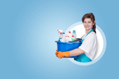 Mavi arka plandaki temizlikçi kadın kova ve temizlik ürünleriyle.