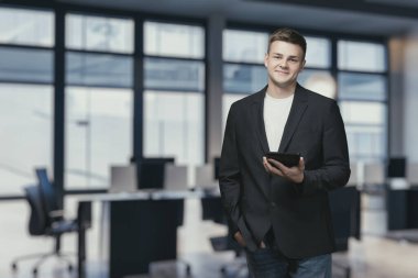 Ofisin arka planında elinde tabletle bir takım elbiseyle müdür..