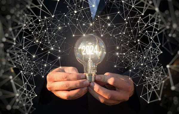 Concept of new business ideas in the new year 2024. A man shows a light bulb with burning numbers 2024.
