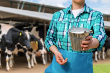 Bir sütçü kız arka planda bir kovada sütü gösteriyor..