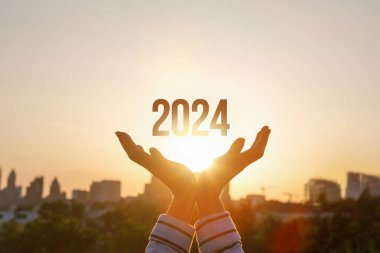 2024, güneşli bir günbatımının arka planında çalışan kadınlar tarafından desteklenmektedir..