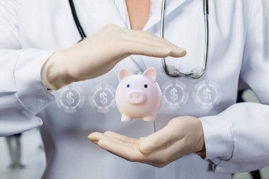 Doktor, domuz kumbarası şeklindeki birikimleri koruyucu bir hareketle koruyor..