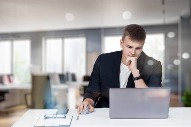 Bulanık ofis geçmişindeki bilgisayarda çalışan genç bir programcı..