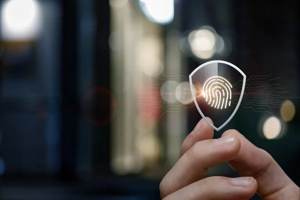 Concept of fingerprint protection when scanning. A hand shows a shield with a print inside on a different background.