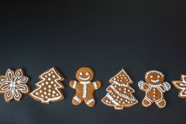 Zencefilli çörekler ve siyah arka planda Noel ağaçları.