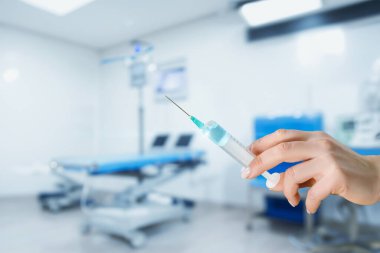 Bulanık arka planda ilaç dolu bir şırınga tutuyor..