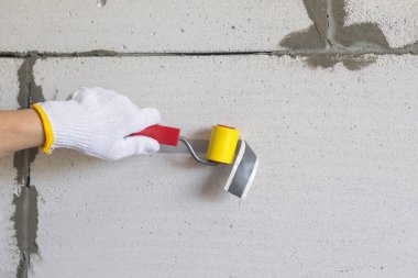Bir inşaat işçisi duvara yapışkan bant yapıştırır..