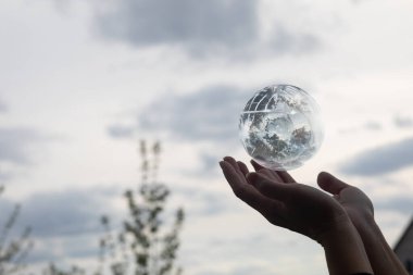 Küresel dünyayı destekleme kavramı. Eller gökyüzüne karşı bir küreyi destekliyor.