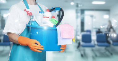 Salonun bulanık arka planında kova ve temizlik malzemeleriyle temizlikçi kadın..