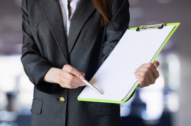 İş elbisesi giymiş bir kadın imza için bir belge tutuyor..