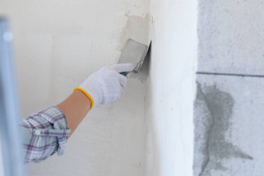 Bir açı spatulası kullanarak bir duvarın köşesini düzleştirme süreci.