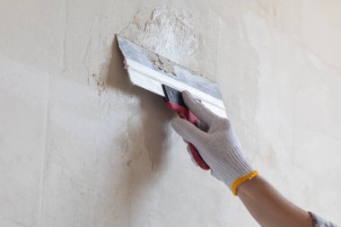 Bir spatula kullanarak macunu duvara sürme işlemi.