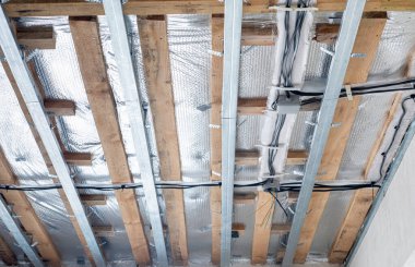 Elektrik kablolarıyla tavan kurulumu. Metal çerçeve ahşap kirişler termal yalıtım filmi ve elektrik kablolarıyla asılmış tavanın kurulum süreci.