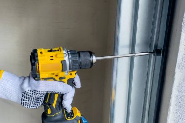 Bir zanaatkar bölüm kapılarını tornavida kullanarak birleştirir. Bölüm kapılarının kurulumu konsepti.