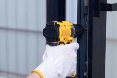 Kapı donanımının kurulumu. Kurucu metal kapıya bir tornavida yerleştirir veya tamir eder.