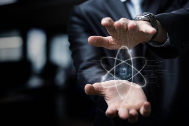 Takım elbiseli bir kişi, modern bir çalışma alanında teknoloji ve yaratıcılığın karışımını gösteren parıldayan bir atom yapısını manipüle ediyor. Atmosfer, ilham verici bir yenilik enerjisiyle doludur..