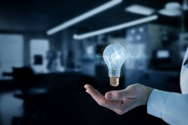 Biyoteknolojide bilimin ve yeniliğin birleşimini sembolize eden çift sarmallı DNA dizaynı içeren bir ampulü bir kişi tutuyor. Arka planda yüksek teknolojili bir laboratuvar ayarları var..