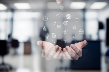 Çağdaş ofis ortamında iki el ileri uzanıyor. Yüzen dijital simgeler iletişimi, teknolojiyi ve veri analizini sembolize eder. Atmosfer profesyonel ve yenilikçi..