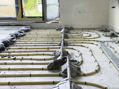 Isıtma boruları yere döşenmiş ve sıcak zemine hazırlanmak için çimentoyla kaplanmış. Bu, yerleşim bölgesinde devam eden çalışmaları gösteriyor, konforu sağlamak için..