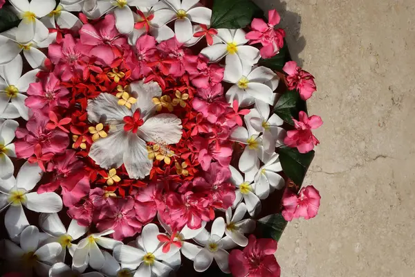Beautiful Floating flower decorations done in large clay flat pot. Flower decoration in water with Plumeria and Oleander flowers with Hibiscus in center. Decoration for festival at home