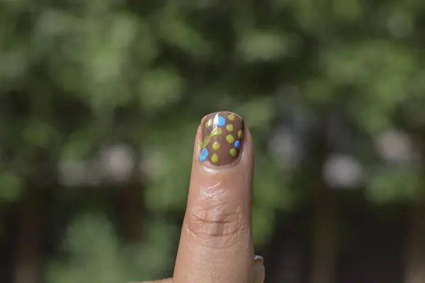 Closeup of Nail art designs, Handmade dots nail design on female index finger. Nail art with colorful dots nail design