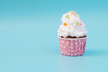 Tasty cup cake on blue background with copy space